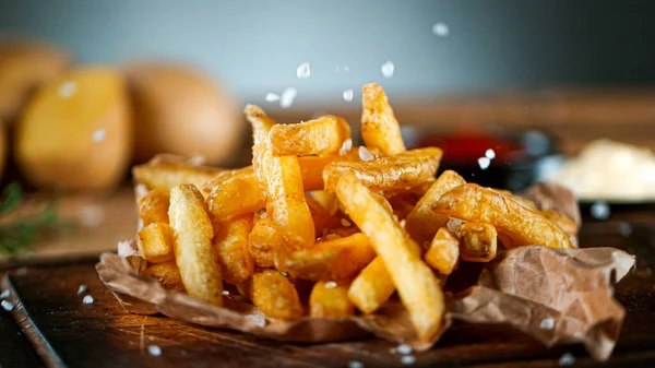 Shot of Falling Fresh French Fries on Wooden Table — Stockfoto