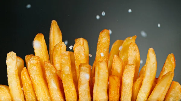 Congelar detalhe do movimento Tiro de adicionar sal em batatas fritas — Fotografia de Stock