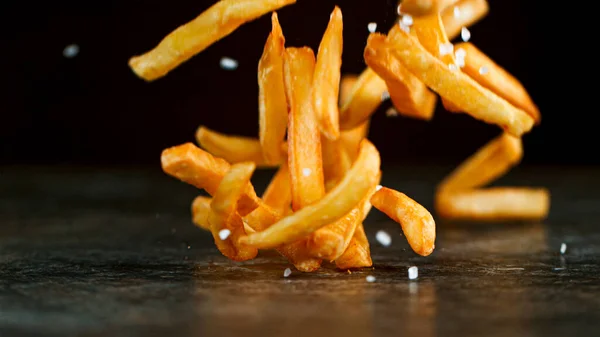 Shot of Falling Fresh French Fries on Wooden Table — Stockfoto