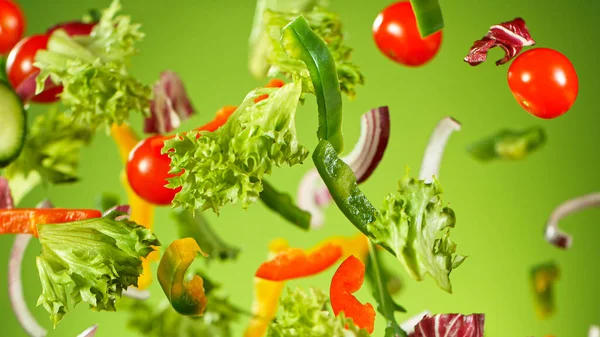 Flying vegetable salad isolated on green background.