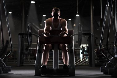 Kaslı genç adam dumbbells ile pazı için kilo egzersiz yapıyor