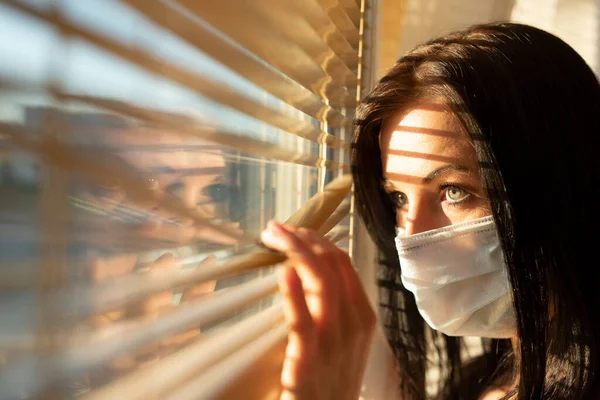 Frau mit Schleier schaut aus dem Fenster ihres Hauses, Konzept der Quarantäne während der Virenpandemie. — Stockfoto