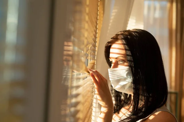 Frau mit Schleier schaut aus dem Fenster ihres Hauses, Konzept der Quarantäne während der Virenpandemie. — Stockfoto