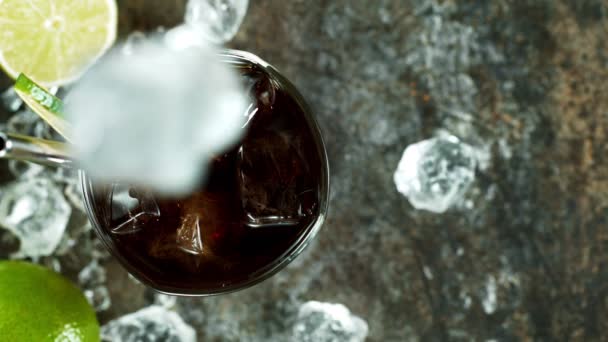 Refrescante cóctel Cuba libre en una copa sobre mesa de piedra negra, macro toma de cámara lenta . — Vídeos de Stock