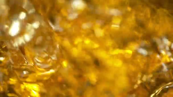Super ralenti prise de vue de l'huile éclaboussante sur fond doré à 1000fps.