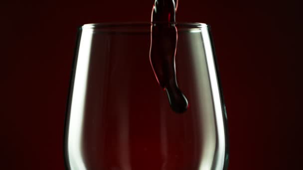 Super Slow Motion Detail shot van het gieten van rode wijn uit de fles op donkere achtergrond. — Stockvideo