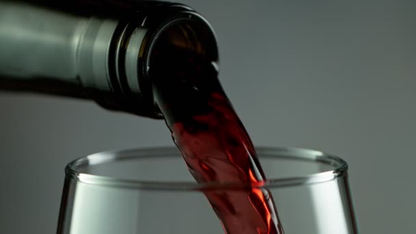 Super Slow Motion Detalle Shot of Verter vino tinto de botella sobre fondo oscuro. — Vídeo de stock