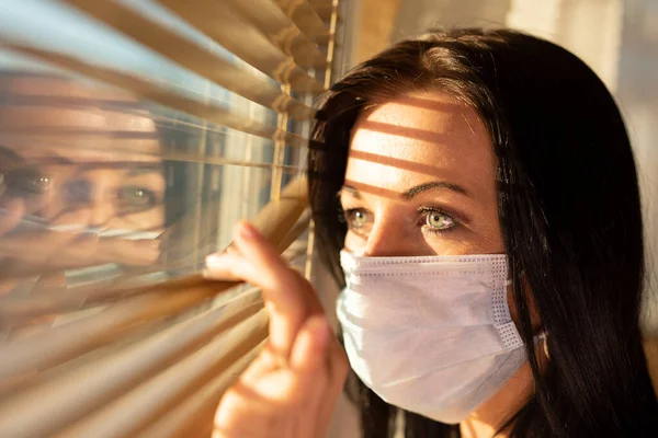 Frau mit Schleier schaut aus dem Fenster ihres Hauses, Konzept der Quarantäne während der Virenpandemie. — Stockfoto