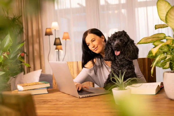 Mladá žena pracuje na svém notebooku se svým pudlím psem — Stock fotografie