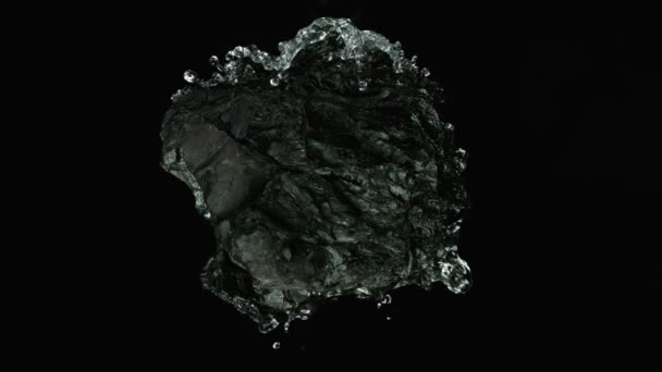 Een stuk steenkool met spetterend water. Cosmetisch concept van huid- en gezichtsverzorging. Langzame beweging. — Stockvideo