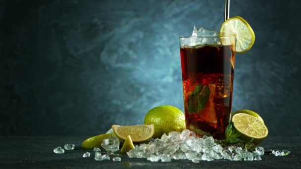 Verfrissende Cuba Libre cocktail in een glas op zwarte stenen tafel, macro slow motion shot. — Stockvideo