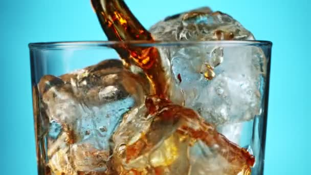 Close up of pouring cola in transparent glass with ice cubes — Stock Video