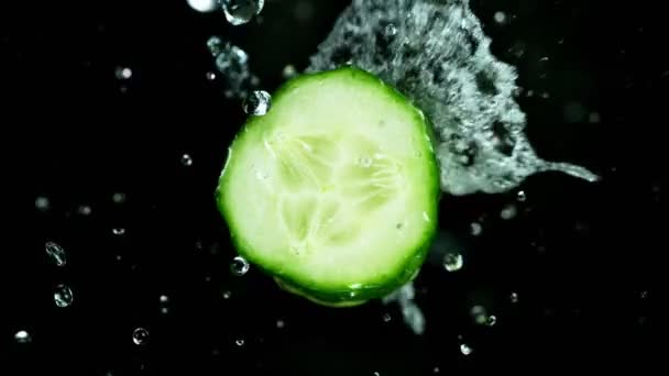 Super lente prise de vue de concombre avec éclaboussures d'eau isolé sur fond noir — Video