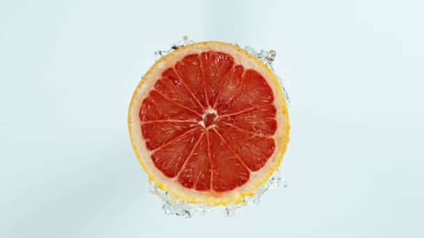 超スローモーション白い背景に分離されたスプラッシュ水でカットグレープフルーツのショット — ストック動画