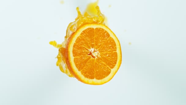 超スローモーション白い背景に分離されたスプラッシングジュースでオレンジスライスのショット — ストック動画