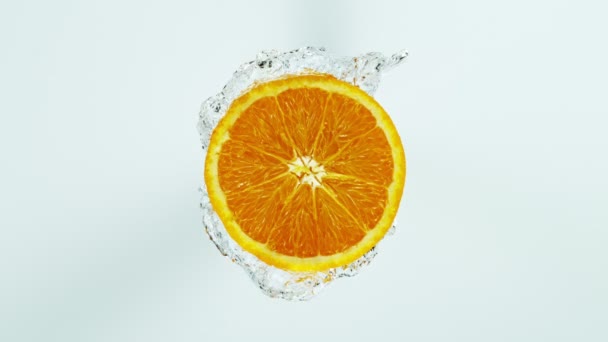 Super Slow Motion Shot de rodaja naranja con agua salpicada aislada sobre fondo blanco — Vídeo de stock