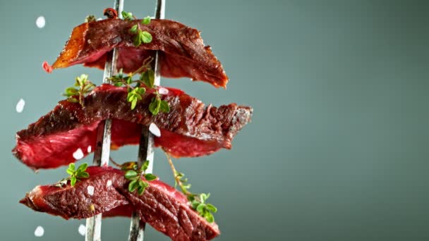 Close-up of beef pieces on fork with falling salt and herbs, slow motion. — Stock Video