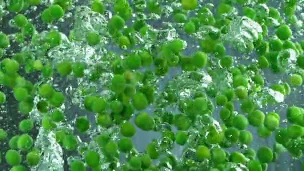 Verse groene erwten in gekookt water, slow motion. — Stockvideo