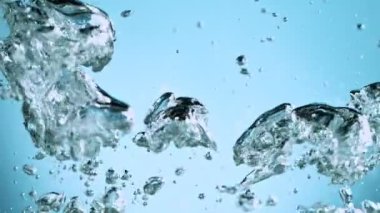 Sudaki çeşitli hava kabarcıklarının makro çekimi açık mavi arka planda yavaş çekimde yükseliyor