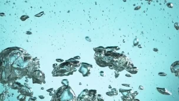 Macro shot of various air bubbles in water rising in slow motion on light blue background — Stock Video