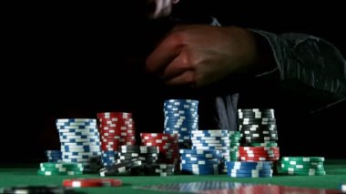 Poker oyuncusu çipleri kameraya doğru atıyor.