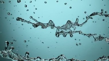 Mavi arka planda su sıçraması, süper yavaş çekim.