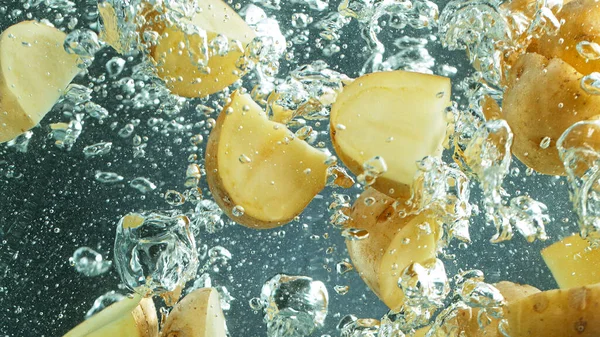 Lanzar trozos de papas en agua hervida, congelar el movimiento . —  Fotos de Stock