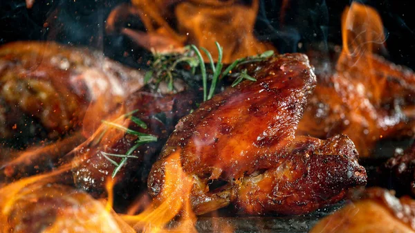 Tasty chicken legs on cast iron grate with fire flames. — Stock Photo, Image