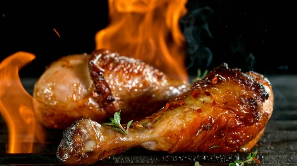Tasty chicken legs on cast iron grate with fire flames. — Stock Photo, Image