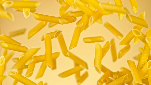 Flyga okokt italiensk pasta penne på guld bakgrund. — Stockfoto