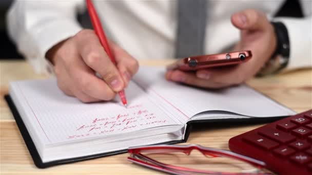 Hands Businessman Using Smartphone And Taking Notes In Diary. Close Up — Stock Video