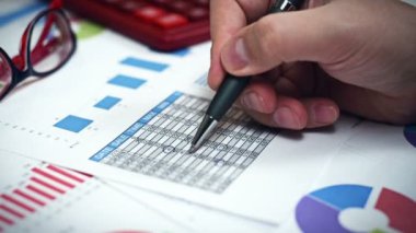 Yatırımcı elinde kalem ile adam ve Menkul Kıymetler Borsası istatistik analiz eder. Yakın çekim