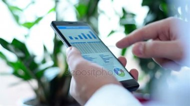 Hareket eden telefon ile mali istatistikler ve hisse senedi grafiği. Yakın çekim
