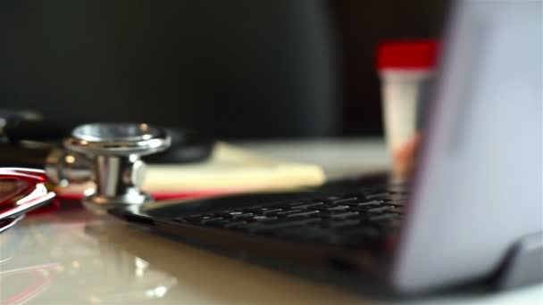 Schránka s předpis seznam, Laptop, Poznámkový blok a stetoskop, ležící na stole — Stock video