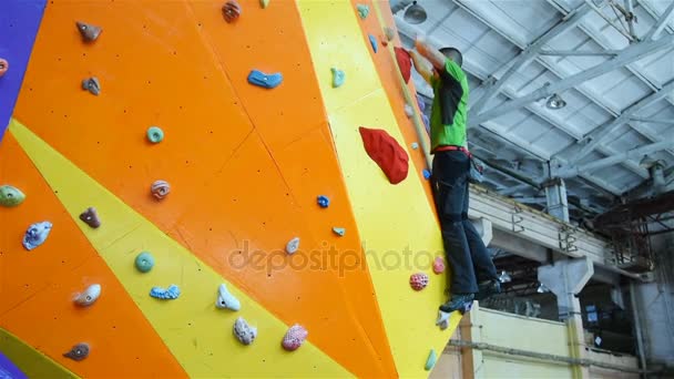 Escalador hombre en artificial escalada pared en bouldering gimnasio — Vídeos de Stock