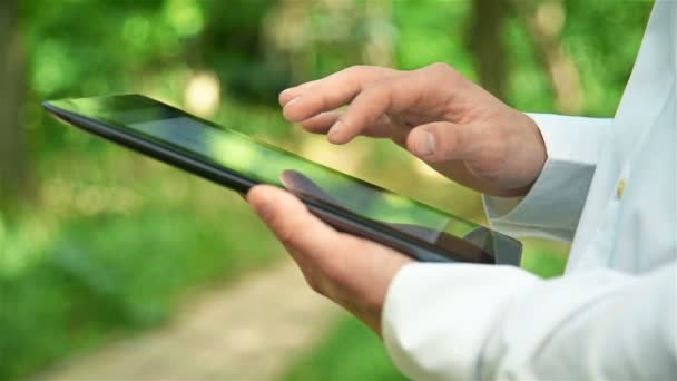 Man van de handelaar controleert of financiële gegevens In touchpad In het Park — Stockvideo