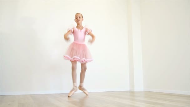 Jovem bailarina no vestido rosa fazendo treino na sala de aula. Efeito de movimento lento — Vídeo de Stock