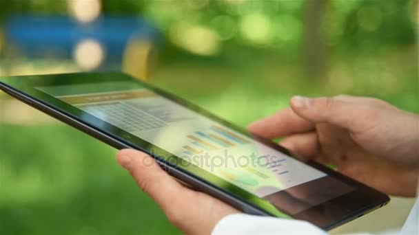 Businessman In Park Analyzing Start Up Report On Touch Pad. Slow Motion Effect — Stock Video
