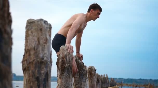 Man Athlete Makes A Stand On His Hands On Wooden Pillars. — Stock Video