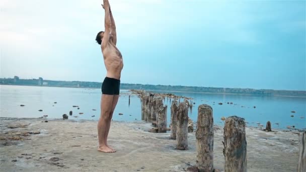 Jeune homme debout pose de yoga sur la rive de la rivière — Video