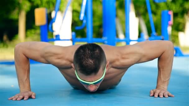 Hombre muscular ejercitando flexiones en el patio de recreo al aire libre. Efecto de cámara lenta . — Vídeos de Stock