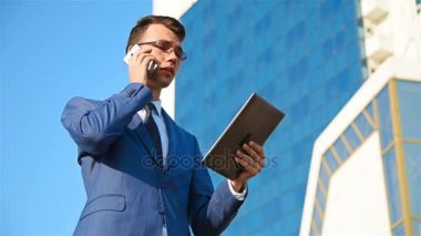 Tablet ile telefonda konuşan işadamı