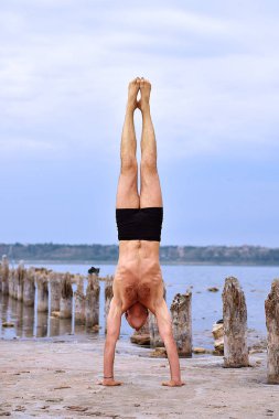 Yoga ayakta bozulmamış plajda ellerinde yapan erkek