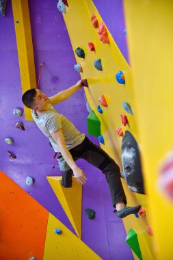 Renkli taş duvar içinde jimnastik salonu üzerinde yukarı tırmanma kas Climber erkeği