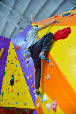 Genç adam spor salonunun duvarına tırmanıyor. Aşırı ve sağlıklı yaşam tarzı konsepti.