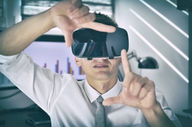 VR kulaklıklı bir iş adamı ofiste oturuyor ve sanal hisse senedi raporlarına bakıyor. İnteraktif İş ve Teknoloji Konsepti. Kapat.