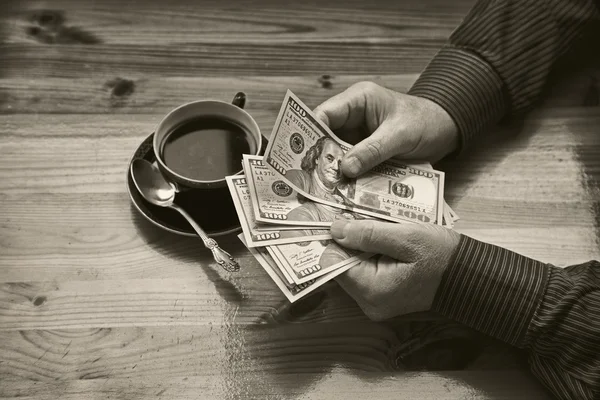 Богатый взрослый мужчина считает доллары и пьет кофе — стоковое фото