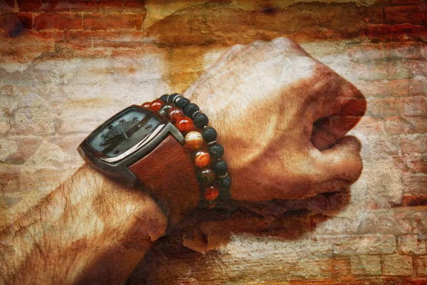 Muro di mattoni e la mano dell'uomo con un orologio e bracciali primo piano — Foto Stock