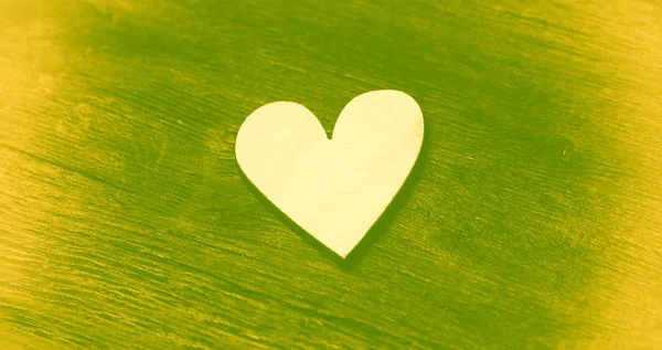 Symbol - Herz auf Vintage-Holzgrund. Grün-gelbe Kunstverarbeitung — Stockfoto