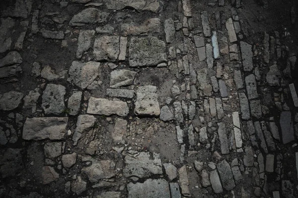 Pavimento de piedra. Vieja carretera pavimentada con piedras. Fondo, textura de piedras y cantos rodados. Estilo oscuro —  Fotos de Stock